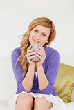 Attractive red-haired woman holding a cup of coffee and posing w