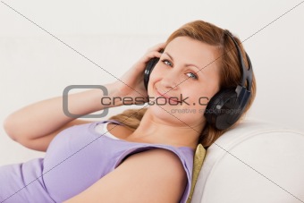 Beautiful blond-haired woman listening to music lying on the sof
