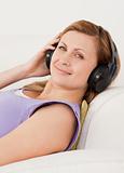 Attractive blond-haired woman listening to music lying on the so
