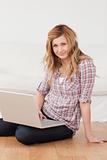 Blonde woman looking at the camera while surfing on her laptop