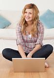Smiling woman looking at the camera while surfing on her laptop