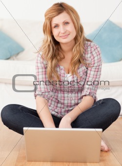 Pretty woman looking at the camera while surfing on her laptop