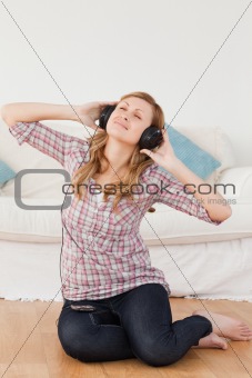 Happy woman listening to music while sitting on the floor