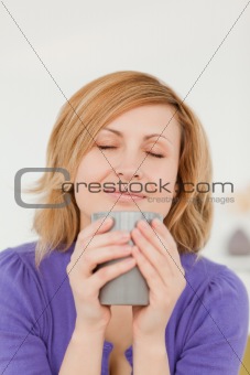 Attractive red-haired woman holding and smelling a cup of coffee