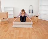 Blond-haired woman rolling up a carpet to prepare to move house 