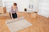 Cute woman rolling up a carpet to prepare to move house