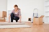 Lovely woman rolling up a carpet to prepare to move house 