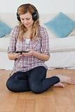 Relaxed blond-haired woman listening to music with headphones