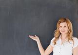Cute female teacher showing an empty blackboard