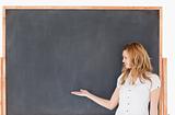 Cute female teacher showing an empty chalkboard