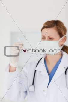 Blond-haired scientist with a mask looking at a test tube