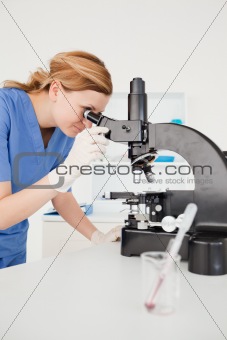 Cute female scientist looking through a microscope