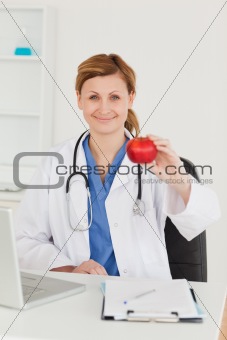 Cute female doctor showing an apple to the camera