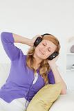 Portrait of a pretty red-haired woman listening to music and enj