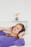 Beautiful red-haired woman listening to music while taking a res