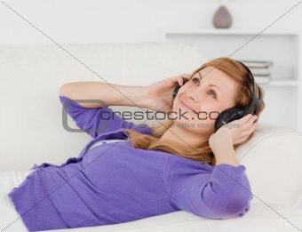 Beautiful red-haired woman listening to music and enjoying the m