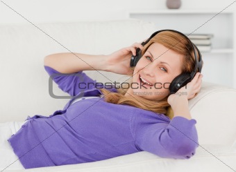 Joyful red-haired woman listening to music and enjoying the mome