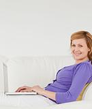Good looking red-haired woman using a laptop and posing while ly