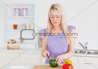 Smiling blonde woman cutting vegetables in modern kitchen interi