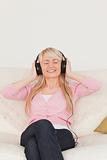 Beautiful female listening to music on her headphones while sitt