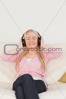 Beautiful female listening to music on her headphones while sitt