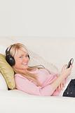 Beautiful female listening to music on her headphones while lyin