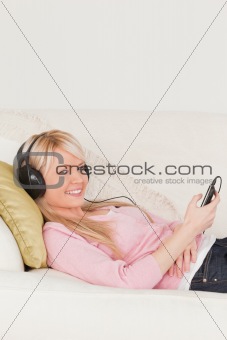 Beautiful female listening to music on her headphones while lyin