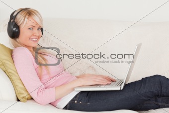 Attractive woman listening to music on her headphones while lyin