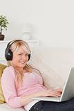 Pretty female listening to music on her headphones while lying o