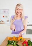 Beautiful blonde woman cutting peppers in modern kitchen interio