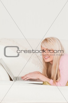 Young female relaxing with a laptop while lying on a sofa