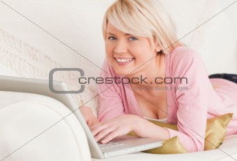 Young attractive female relaxing with a laptop while lying on a 
