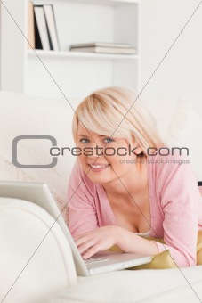Young good looking woman relaxing with a laptop while lying on a