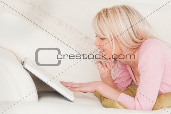 Young beautiful woman reading while lying on a sofa