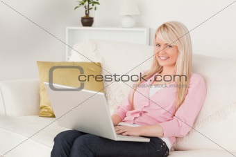 Young good looking female relaxing with a laptop while sitting o