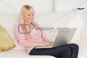 Young smiling woman relaxing with a laptop while sitting on a so