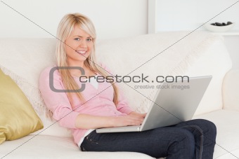 Young smiling female relaxing with a laptop while sitting on a s