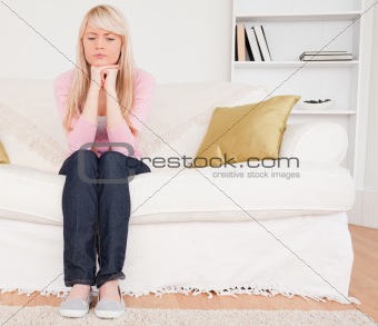 Good looking pensive female sitting on a sofa