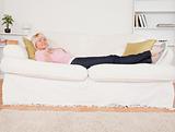 Pretty blonde female watching tv while lying on a sofa