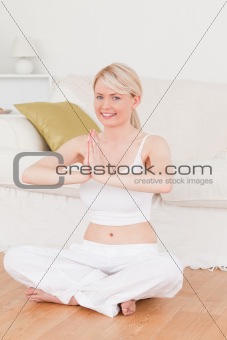 Young blonde female doing yoga in the living room