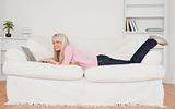 Young blonde woman posing with her laptop while lying on a sofa