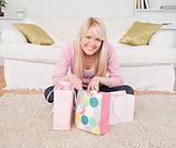 Smiling blonde woman sitting in the living-room with her shoppin