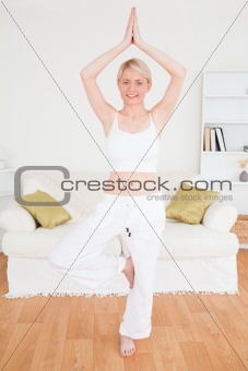 Young happy woman doing yoga in the living room