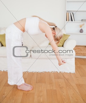 Attractive blonde female stretching in the living room