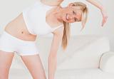 Attractive blonde female posing while stretching in the living r