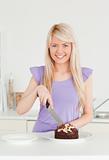 Beautiful blonde female cutting a cake in a plate