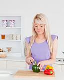 Attractive blonde woman cutting vegetables in modern kitchen int