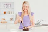 Smiling blonde woman cutting a cake in a plate