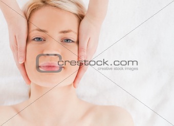 Happy blond-haired woman getting a massage on her face