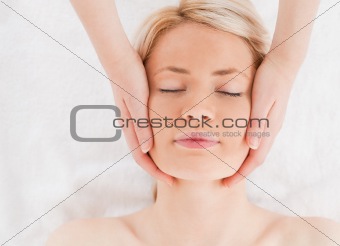 Relaxed blond-haired woman getting a massage on her face